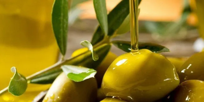 Tavola imbandita con olio extravergine, pane e verdure, simboli della dieta mediterranea
