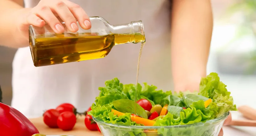 Cucchiaio di olio extravergine di oliva versato su un piatto