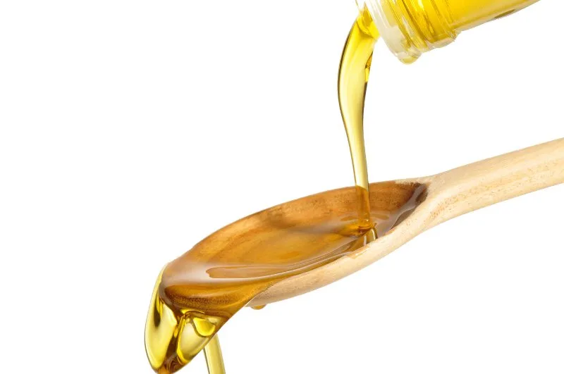 Bicchiere di olio extravergine di oliva osservato in controluce per valutarne colore e limpidezza