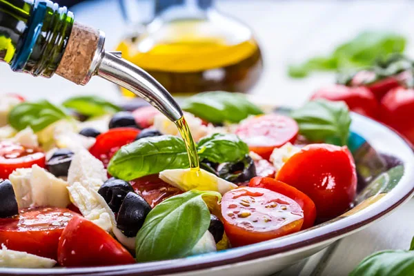 Bottiglia di olio extravergine d'oliva versato al centro della dieta mediterranea