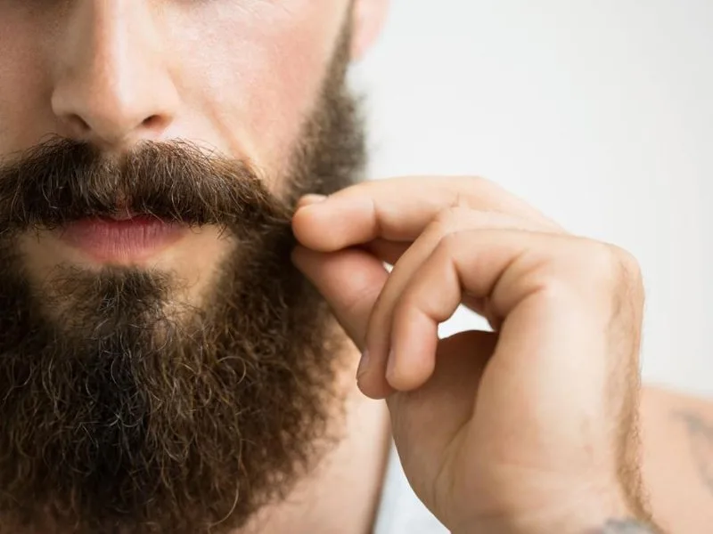 Uomo che applica dell'olio d'oliva sulla barba per idratarla