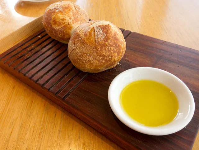 Bottiglia di olio extravergine con riflessi che vanno dal verde al giallo paglierino