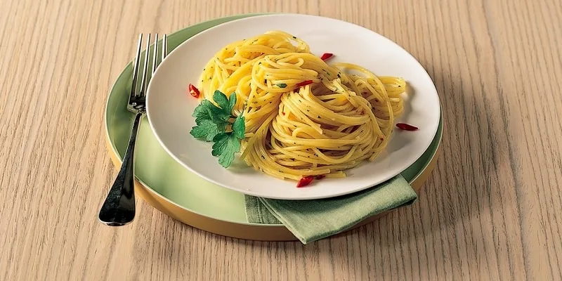 Bottiglia di olio extravergine pugliese Olio Cristofaro con piatti della tradizione mediterranea