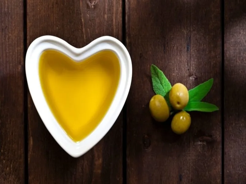 Cuore stilizzato circondato da olive e olio extravergine, simbolo della salute cardiovascolare