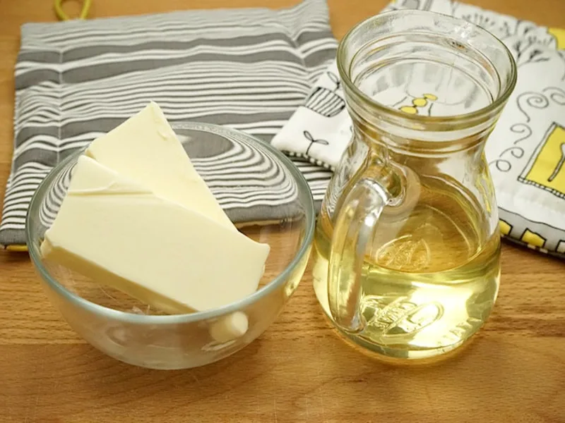 Bottiglia di olio d'oliva accanto a burro e margarina su un tagliere