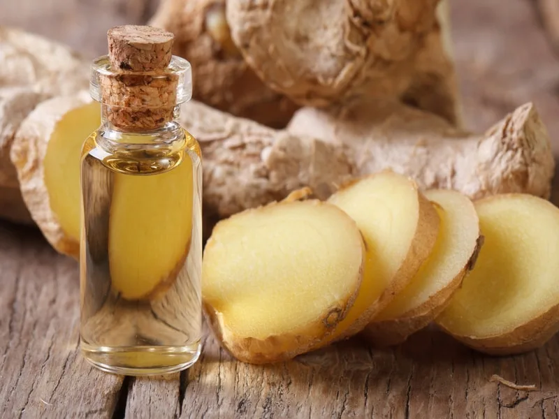Radice di zenzero fresca accanto a una bottiglia di olio extravergine di oliva