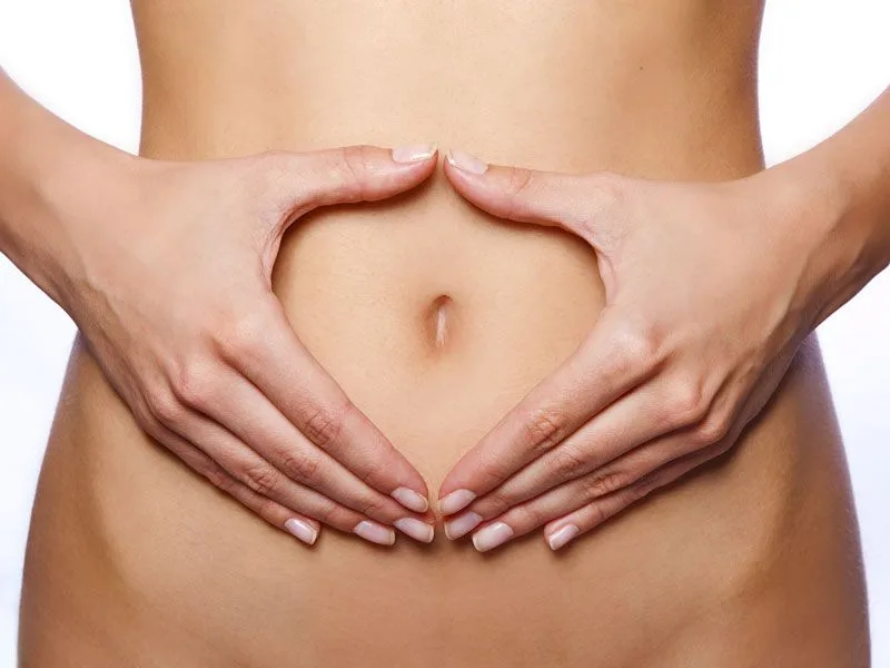 Mani che applicano delicatamente olio extravergine di oliva sull'ombelico per la cura del corpo