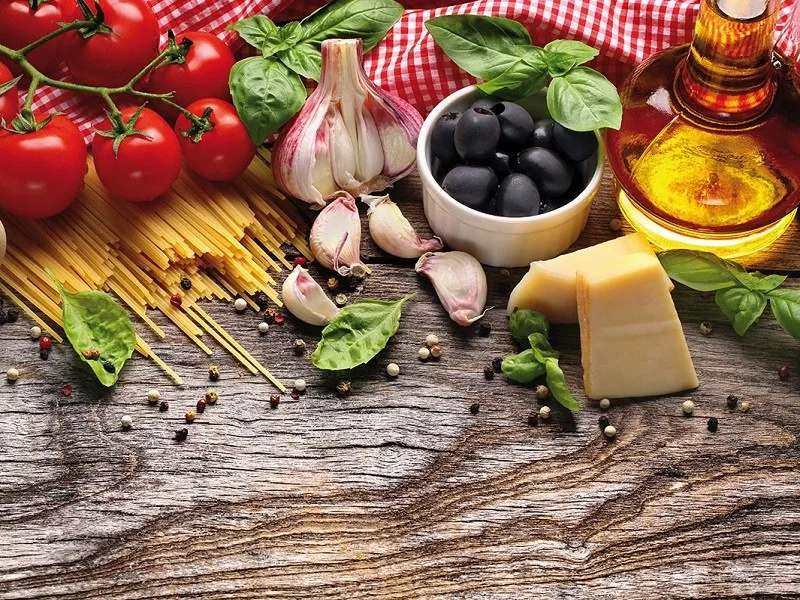Tavola imbandita con olio extravergine, pane e verdure simbolo della Dieta Mediterranea