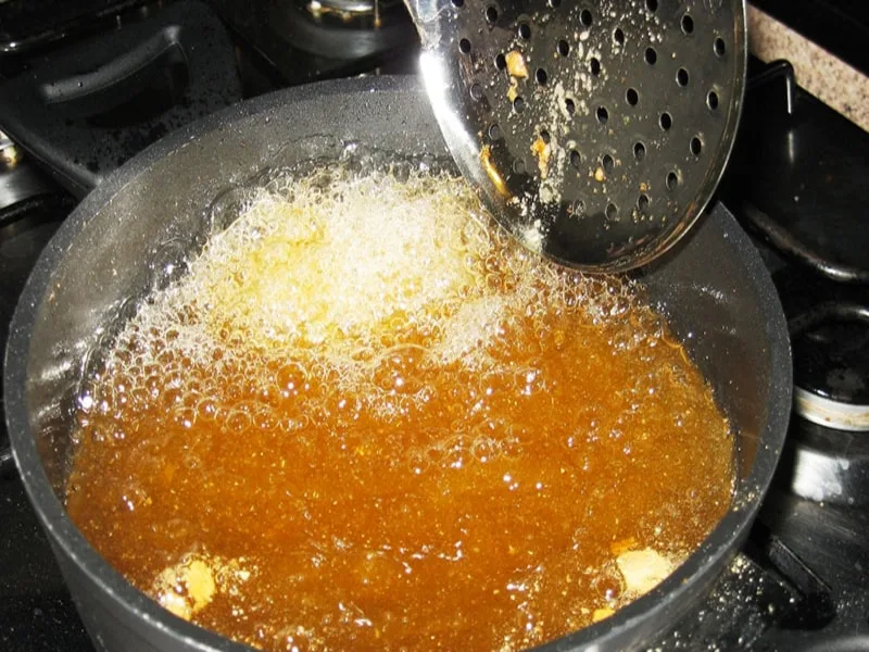 Olio esausto raccolto in una pentola dopo la frittura, pronto per lo smaltimento