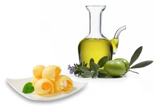 Bottiglia di olio extravergine e panetto di burro a confronto su un tagliere