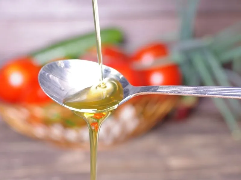 Bottiglia di Olio Cristofaro accanto a olive fresche, simbolo delle proprietà salutistiche dell'Olio Evo