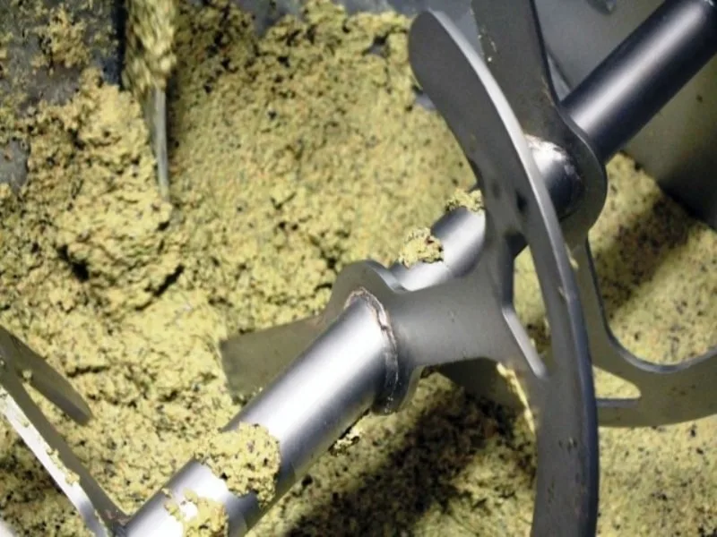 Pale elicoidali della gramola che rimescolano lentamente la pasta di olive