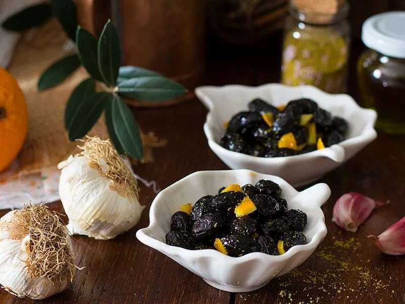 Olive nere in salamoia con scorza d'arancia, aglio e alloro pronte per essere condite