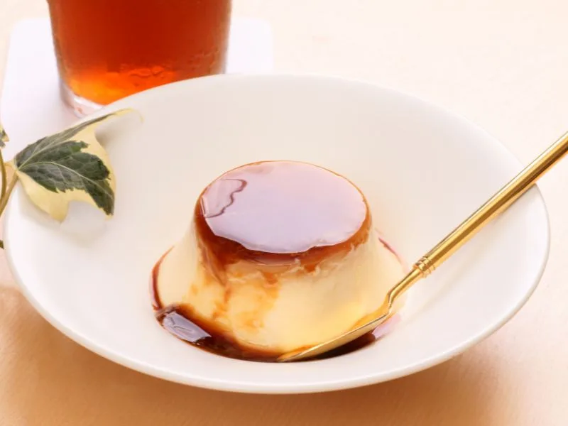 Budino cremoso con olio extravergine d'oliva servito in coppetta, decorato con scorza di limone