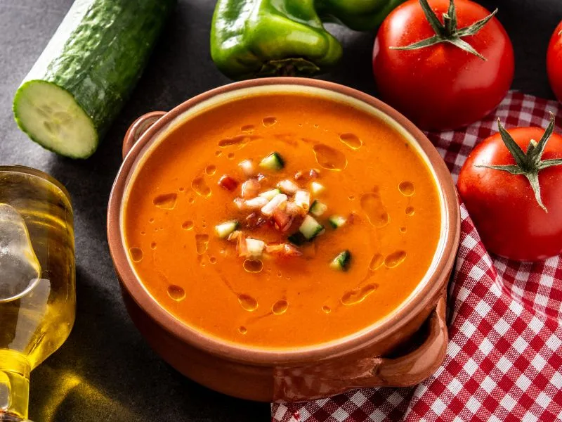 Ciotola di gazpacho fresco guarnito con un filo di olio extravergine di oliva e peperoni arrostiti