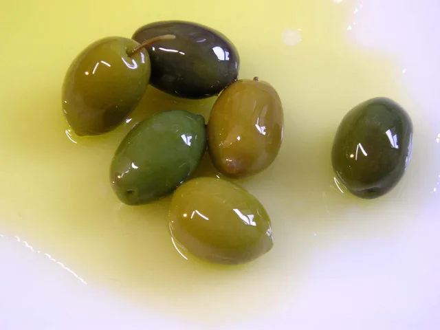 Bottiglia di olio extravergine d'oliva pugliese versato in una ciotola, simbolo dei benefici per intestino e cuore