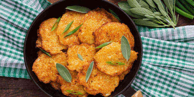 Bottiglia di olio extravergine biologico Olio Cristofaro accanto a una frittura dorata e croccante