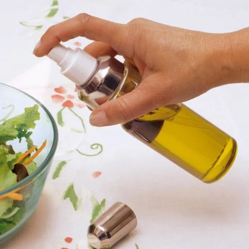 Flacone spray nebulizzatore per olio extravergine di oliva su un piatto pronto da condire