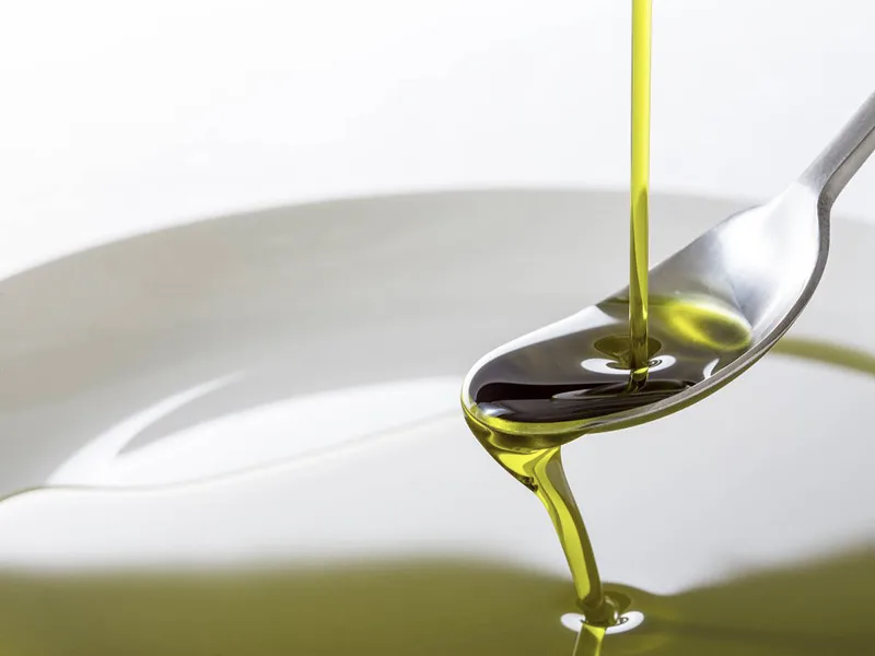 Cucchiaio di olio extravergine di oliva versato come un rimedio naturale