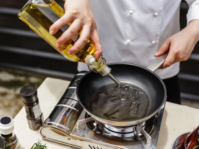 Bottiglia di olio extravergine di oliva versato su un piatto in cucina