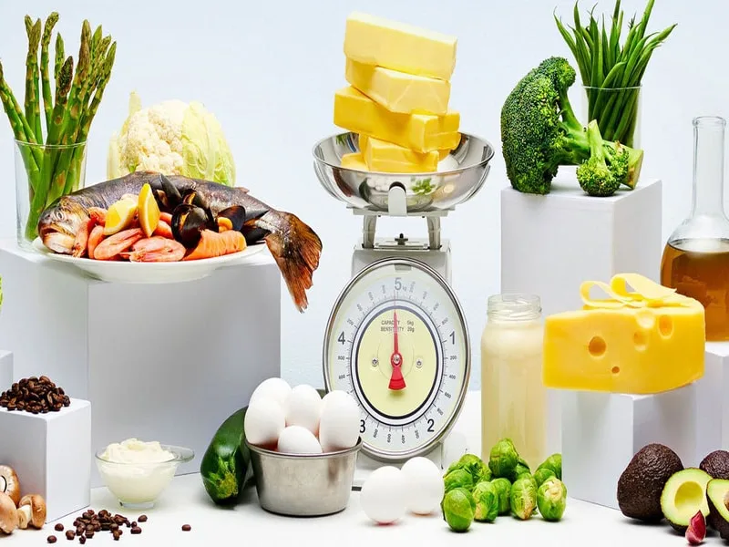Cucchiaio di olio extravergine di oliva accanto a un piatto di verdure per una dieta ipocalorica