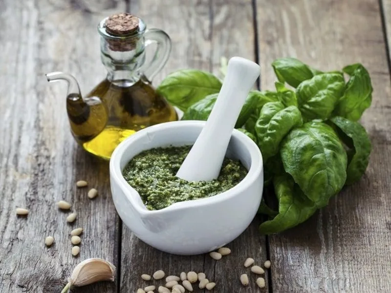 Pesto fresco al basilico preparato con olio extravergine di oliva in un mortaio di legno