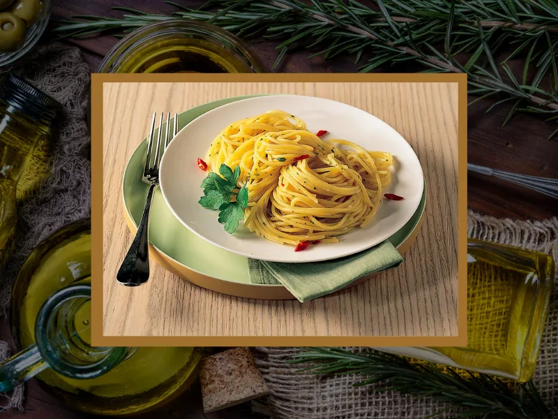 Olio extravergine di oliva versato su un piatto di spaghetti aglio, olio e peperoncino