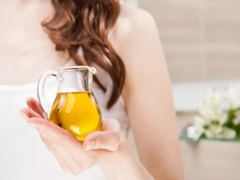 Mani che applicano delicatamente olio extravergine di oliva sulla pelle, rimedio naturale contro la dermatite atopica