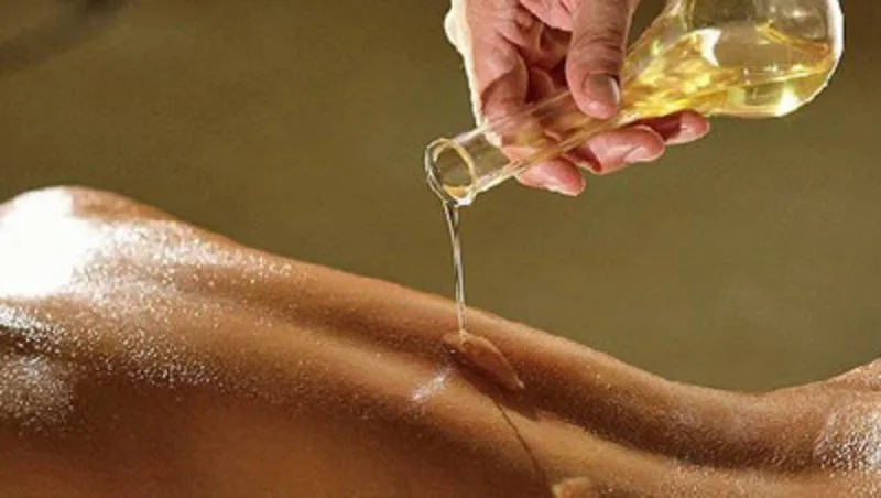 Mani che massaggiano il corpo con olio di oliva