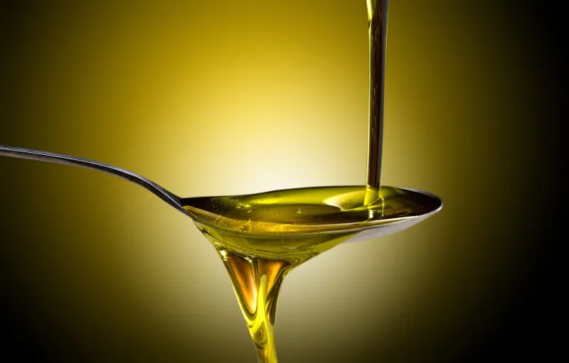 Filo d'olio extravergine versato, simbolo del peso specifico dell'olio di oliva