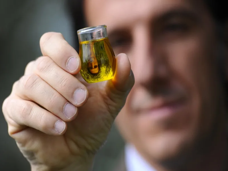 Bottiglia di olio extravergine di oliva versato, dal colore intenso e dal gusto amaro caratteristico