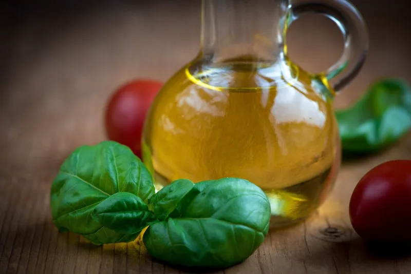 Bottiglia di olio extravergine aromatizzato al basilico con foglie fresche