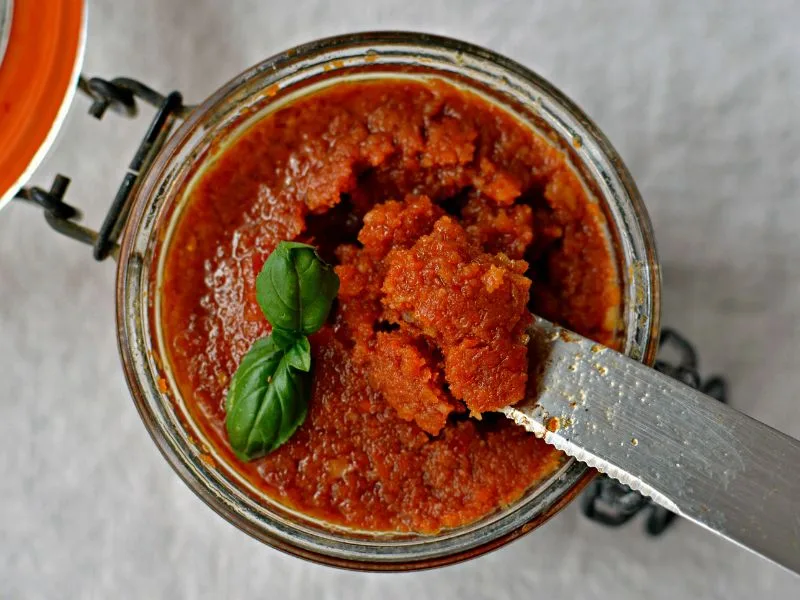 Pesto di pomodori secchi e noci condito con olio extravergine di oliva, servito in un piccolo vasetto