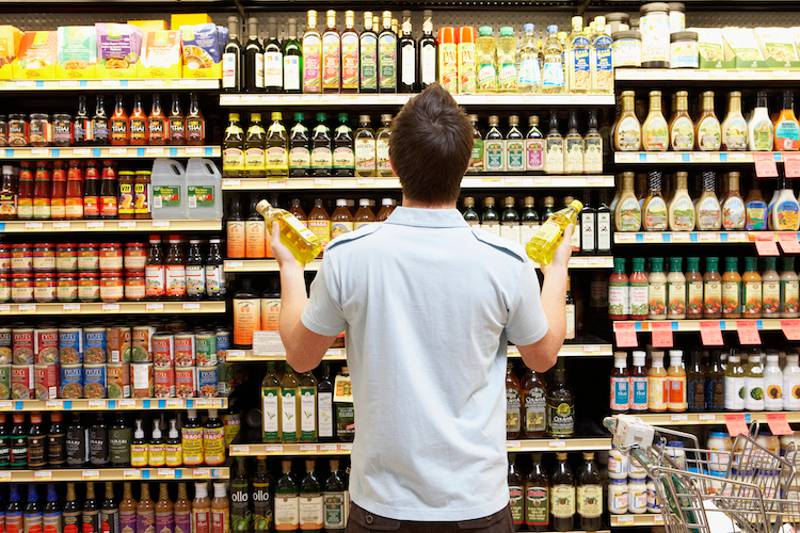Etichetta con data di scadenza su una bottiglia di olio di oliva prelevata da uno scaffale del supermercato