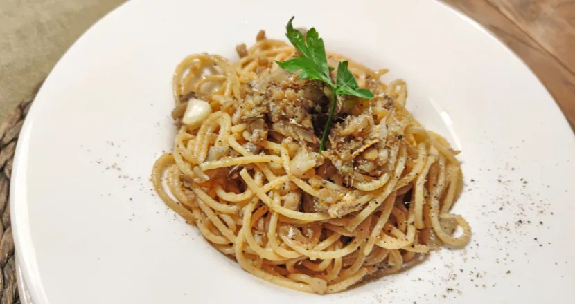 Piatto di spaghetti con acciughe sott'olio, pangrattato tostato e prezzemolo