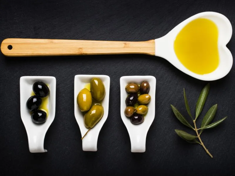 Bottiglia di olio extravergine biologico Olio Cristofaro tra le olive appena raccolte