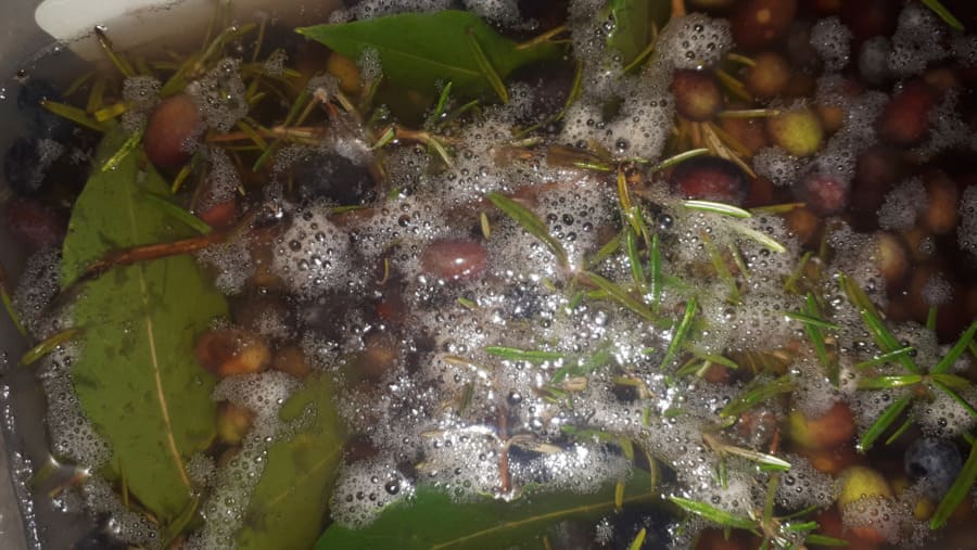 Schiuma e patina sulla superficie dell'acqua durante la salamoia delle olive