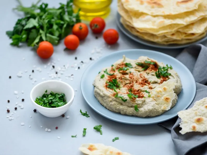 Baba Ganoush cremoso servito in ciotola con un filo di olio extravergine d'oliva pugliese e prezzemolo fresco