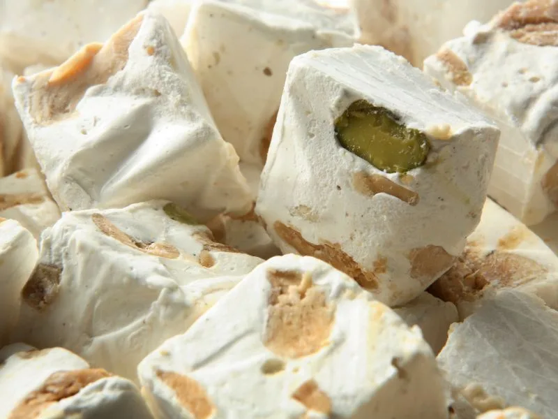 Fudge al cioccolato bianco con pistacchi e olio extravergine di oliva tagliato a cubetti su un piatto da dessert