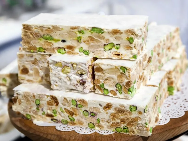Torrone morbido all'olio d'oliva e pistacchi tagliato a pezzi su un piano di legno