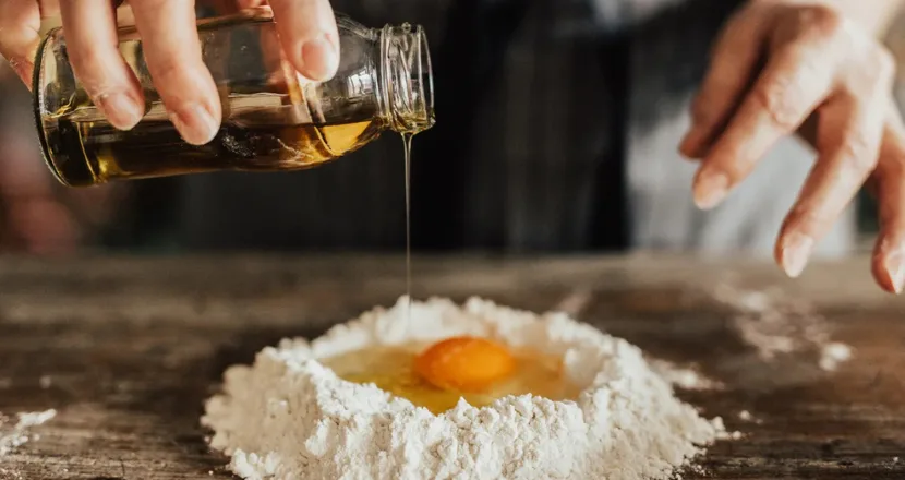 Torta dolce preparata con olio extravergine biologico versato da una brocca