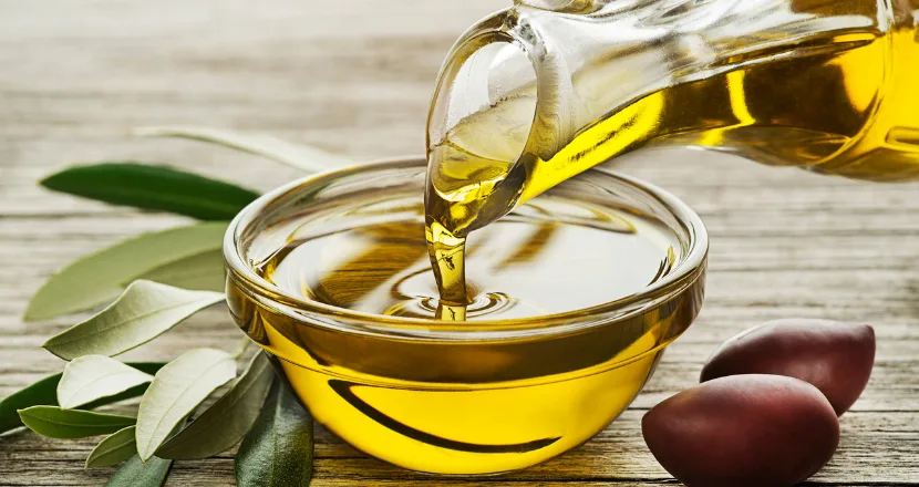 Bottiglia di olio extravergine di oliva Cristofaro accanto a olive fresche, simbolo della tradizione gastronomica pugliese